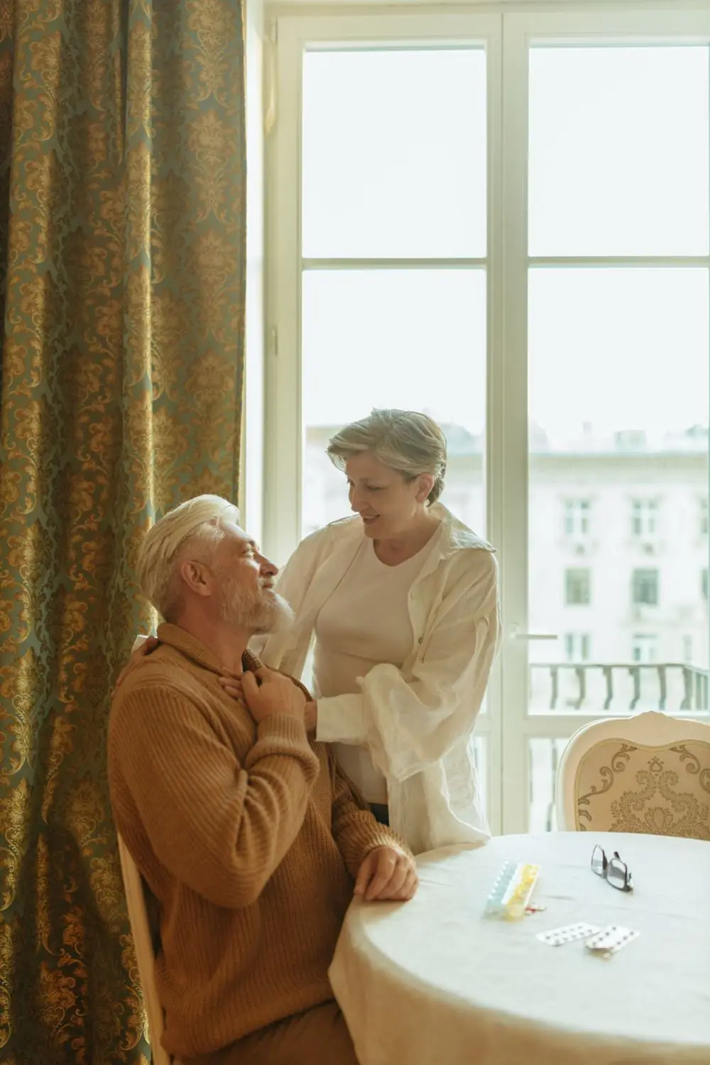 A caregiver smiling with an older man at his kitchen table