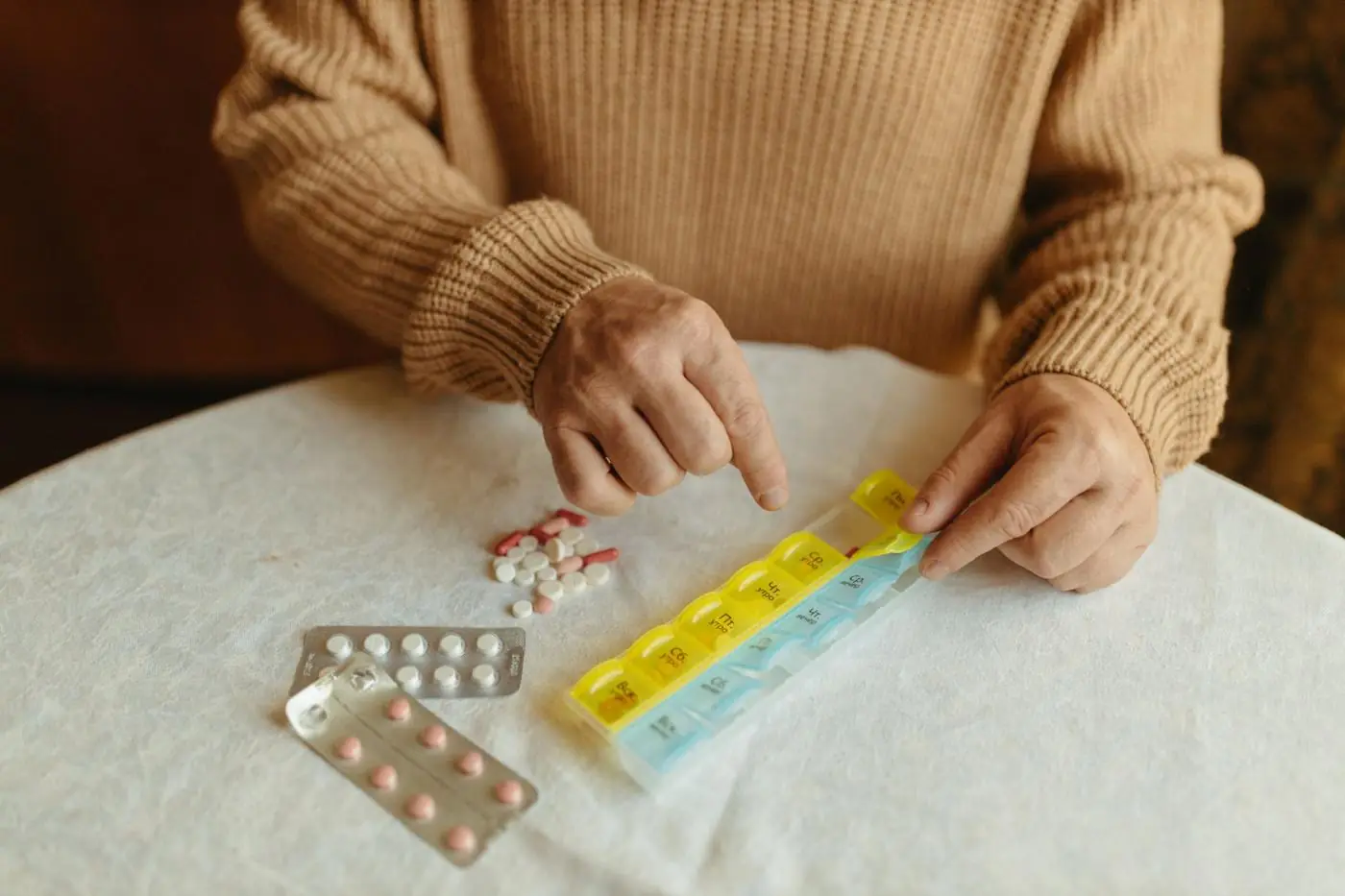 An older man sorting a weekly pill organizer at his table